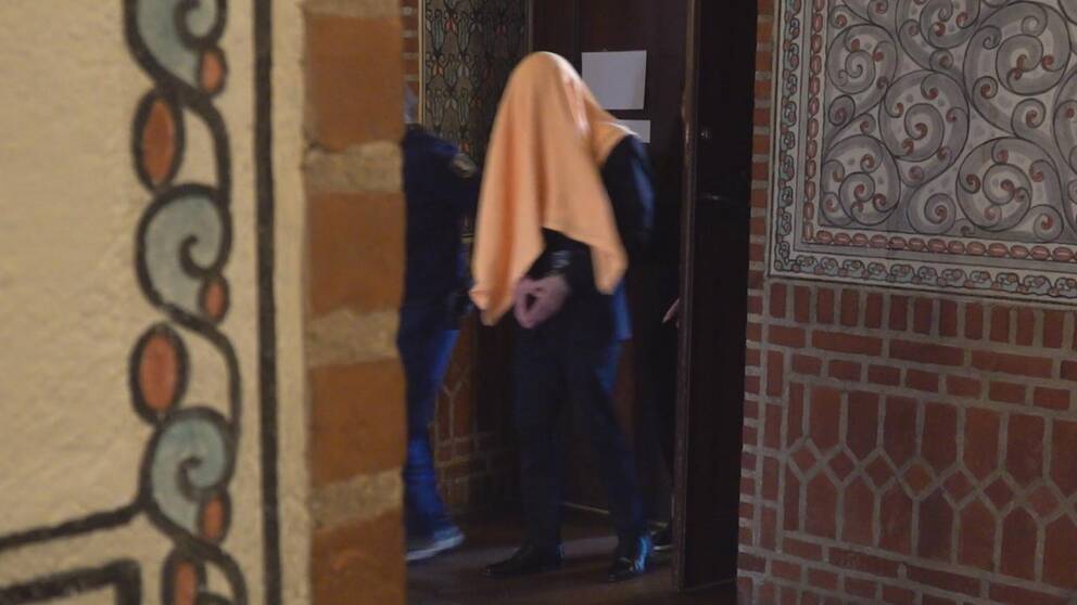 En bild på 22-åringen gåendes ut rättssalen med en gul handduk över huvudet