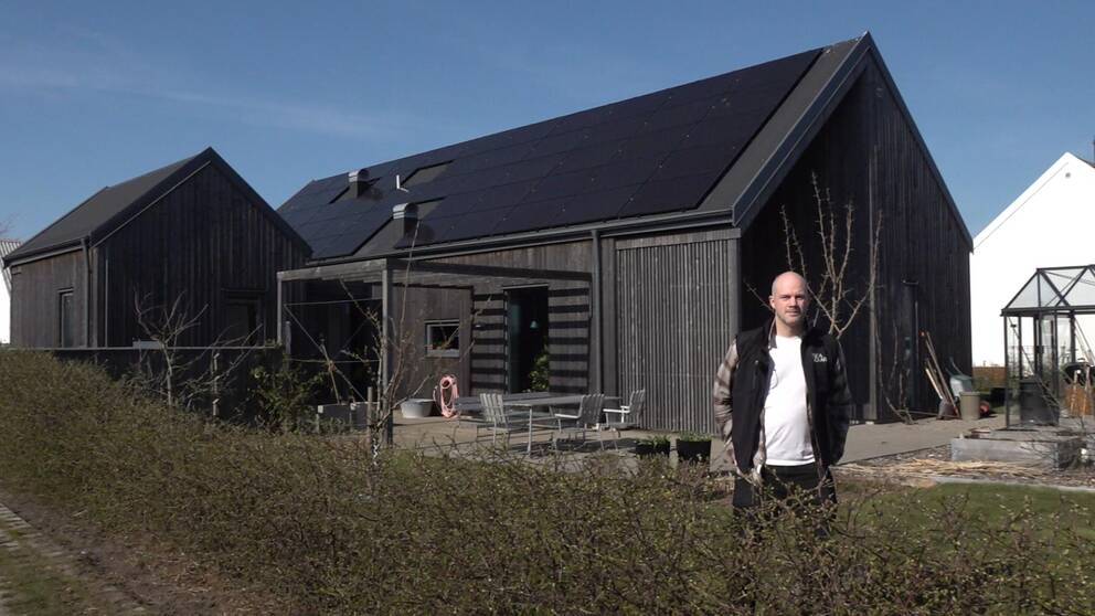 Solcellsmontören Simon Philblad står vid ett hus med solceller på taket.