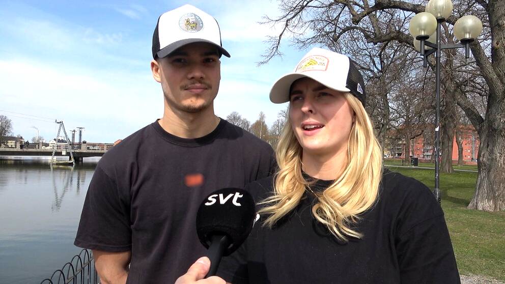 En ung kille och en ung tjej, båda ikädda svarta T-tröjor och kepsar.