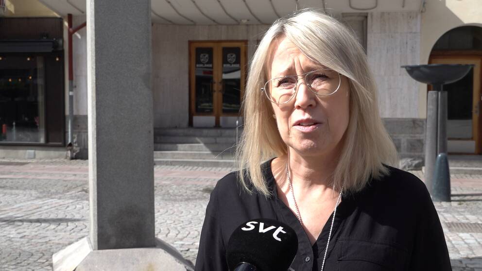 Kvinna i svart skjorta och glasögon framför en dörr.