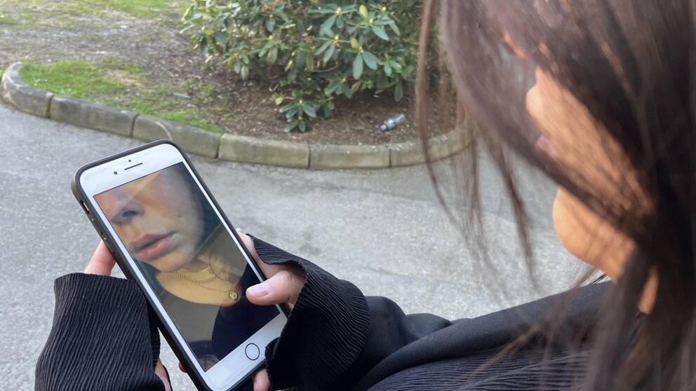 En ung kvinna fotar sig själv med telefonen.