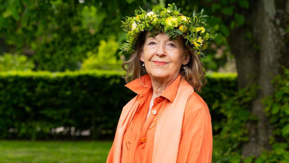 Eva Armini utsedd till Lyssnarnas sommarvärd sommaren 2023. Här står hon i en solig park.