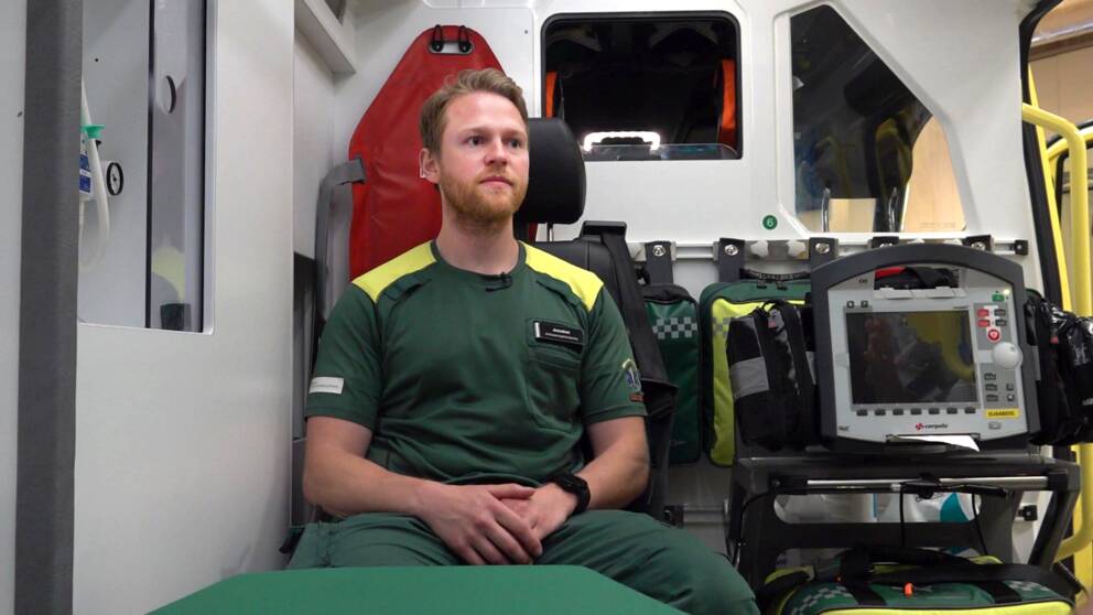 Ambulanssjuksköterskan Jonatan Jardevall sitter i en ambulans. Ung kille med kort hår och skägg.