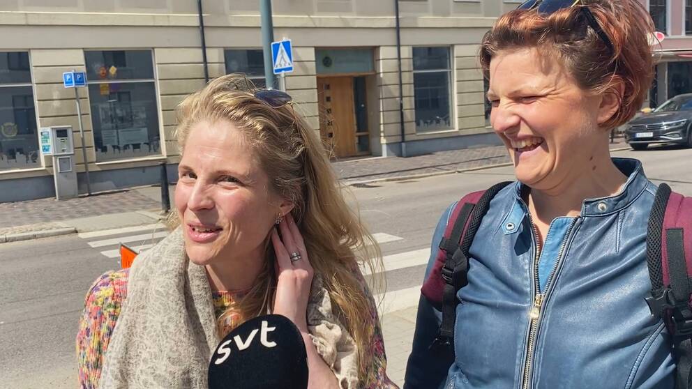 Två kvinnor på gatan i Landskrona, den ena visar upp sina örhängen och den andra skrattar.