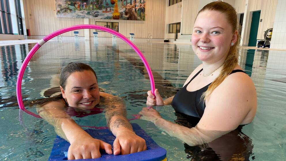 Två tjejer som är simlärare i en bassäng