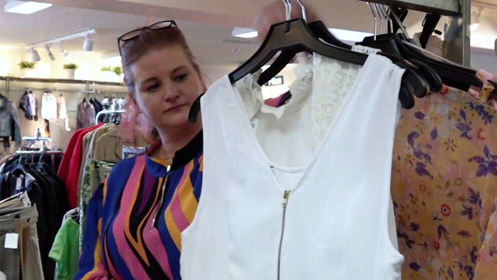 Åsa Ekered visar upp en vit studentklänning i Myrornas butik i Jönköping