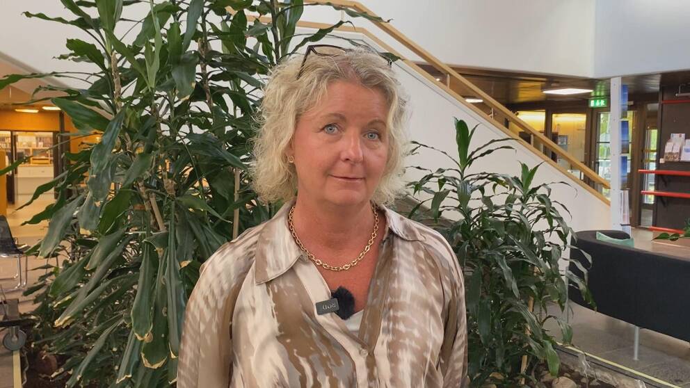 Tina Svensson-Hammargård, chef bildningsförvaltningen, står framför en stor grön växt med en trappa och offentliga lokaler i bakgrunden.