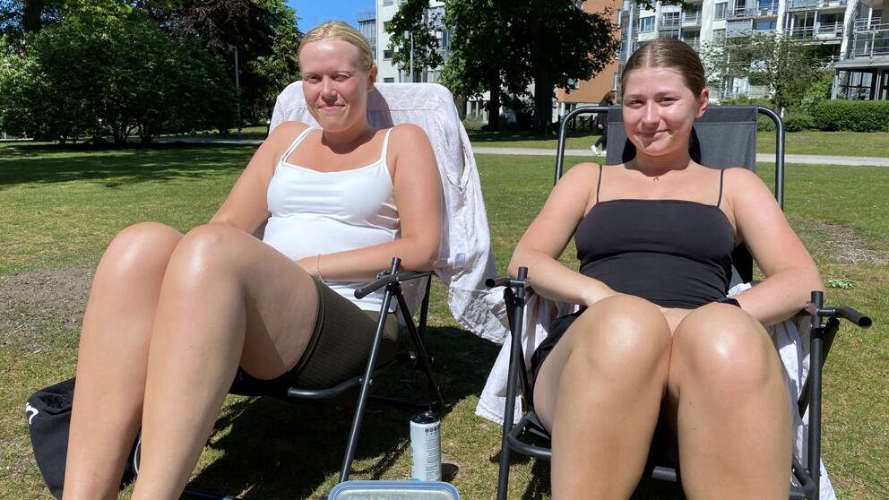 Johanna Ekstrand och Elsa Johansson i solstolar på gräsmattan utanför stadsbiblioteket i Halmstad.