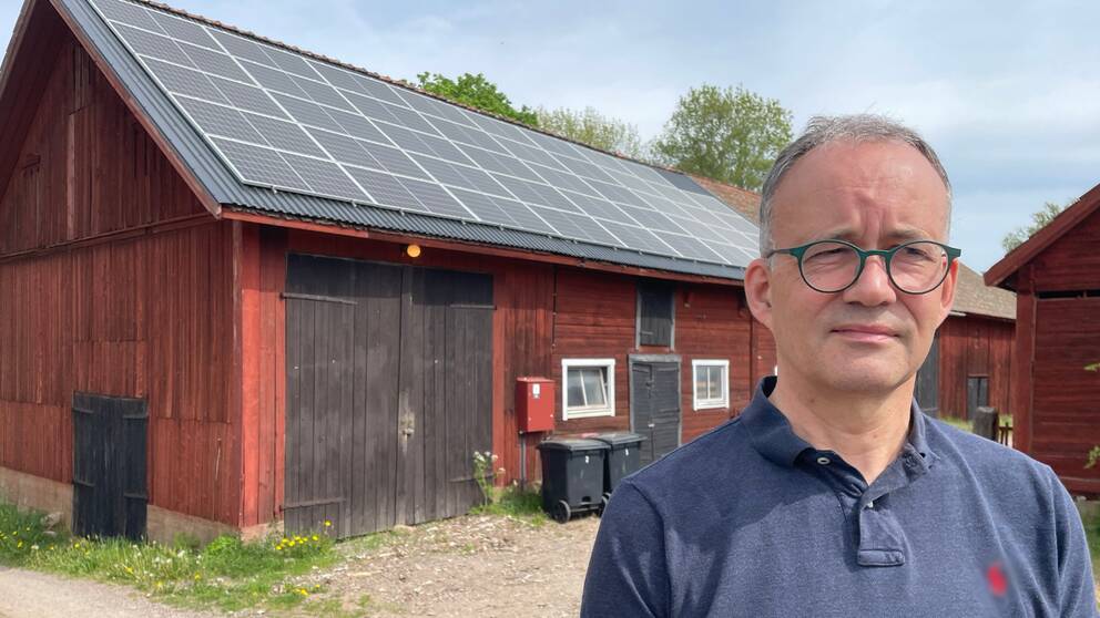 En man står framför ett rött hus.