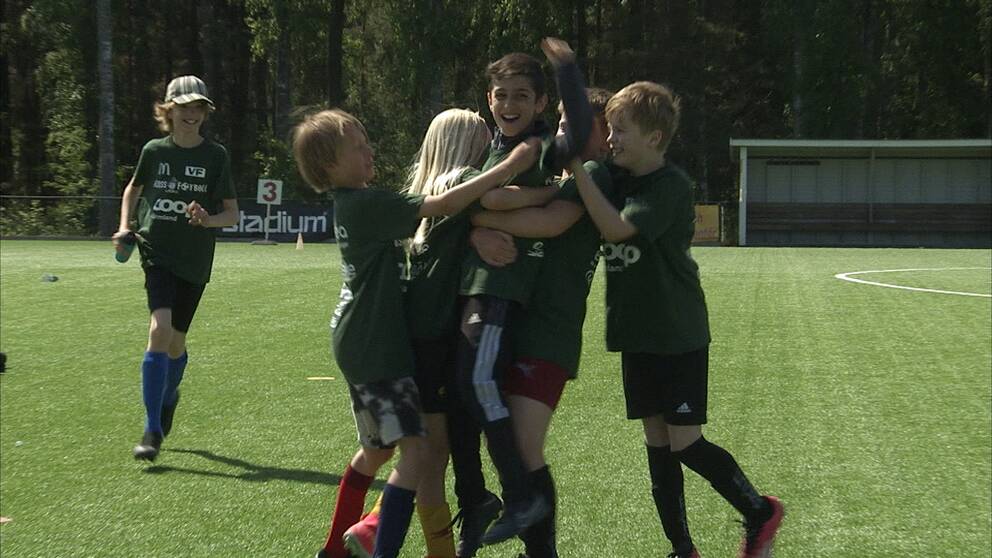 Barn som jublar och klappar om varandra på en fotbollsmatch