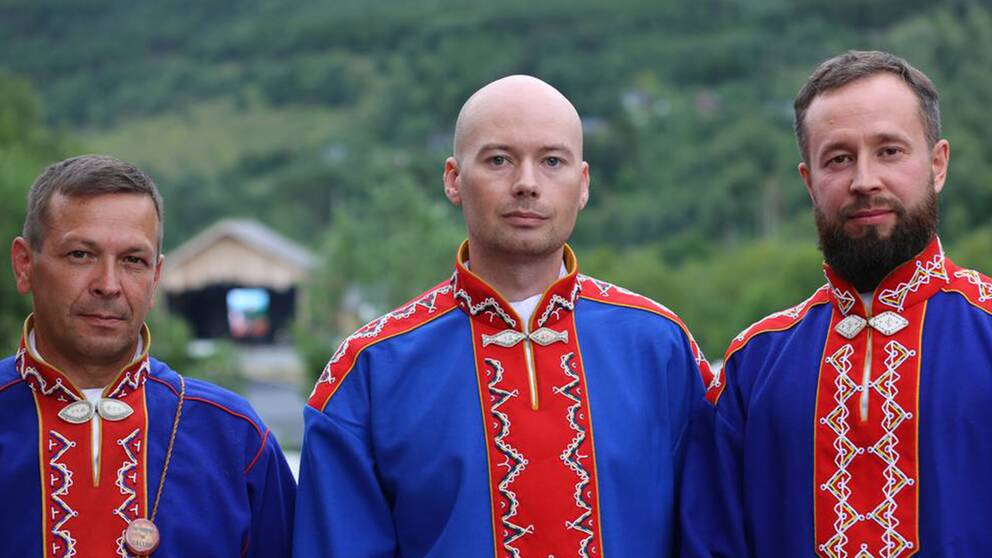 Tre allvarliga män i i blåröda ryska koltar.