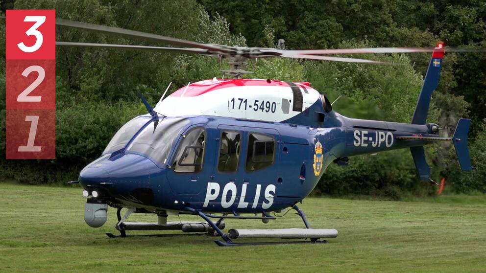 En blå polishelikopter på en gräsmatta.