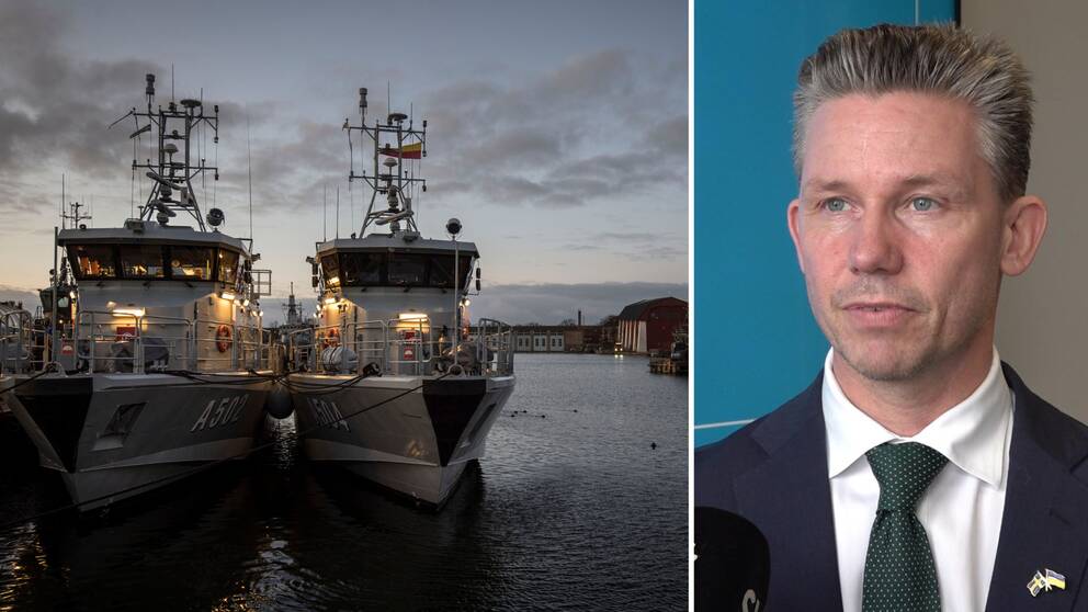 Till vänster två av försvarsmaktensbåtar i mörk hamn, Marinbasen Karlskrona. Till höger man med kort hår, vit skjorta och svart kavaj tittar snett till vänster i bild. Försvarsminister Pål Jonson, Moderaterna.