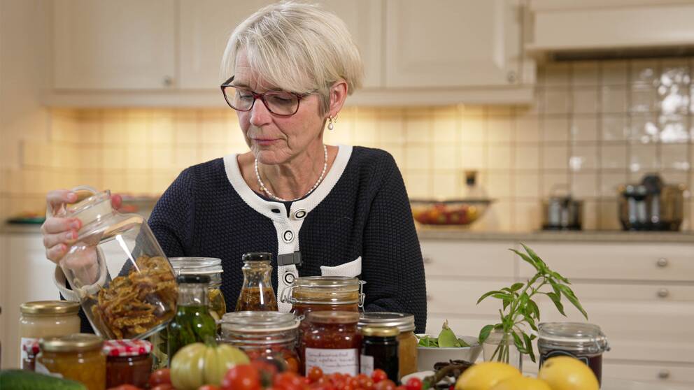 Livsmedelsverkets mikrobiolog Åsa Rosengren står vid ett bord med grönsaker i glasburkar.