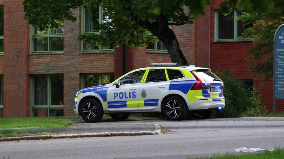 Polisbil framför byggnad i rött tegel
