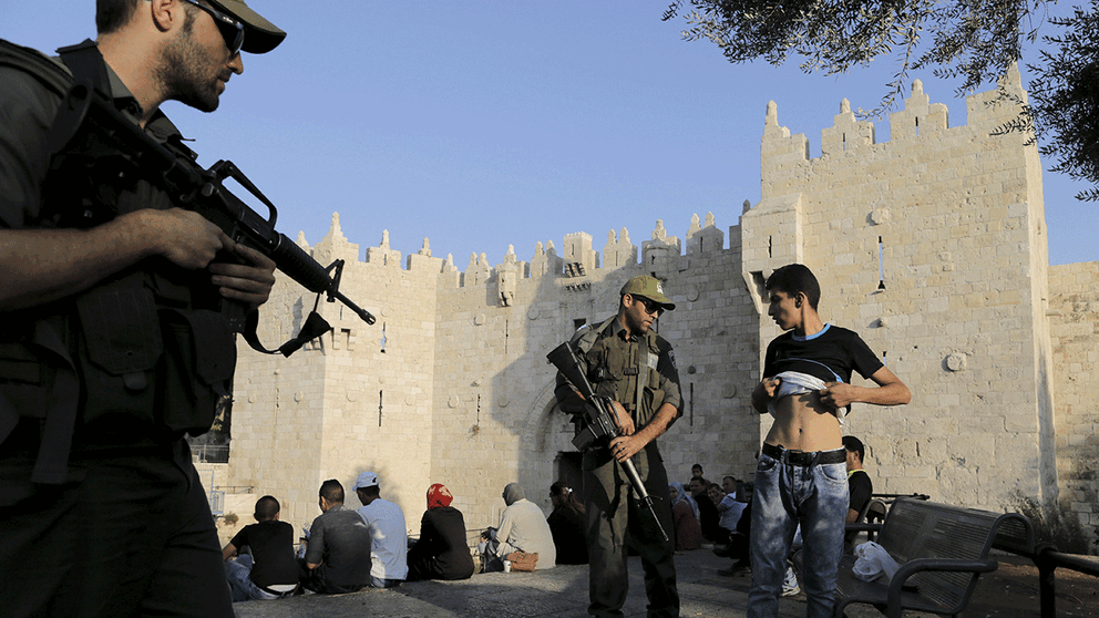 Israelisk polis kontrollerar en ung palestinsk man vid Damaskusporten i Jerusalems gamla kvarter.