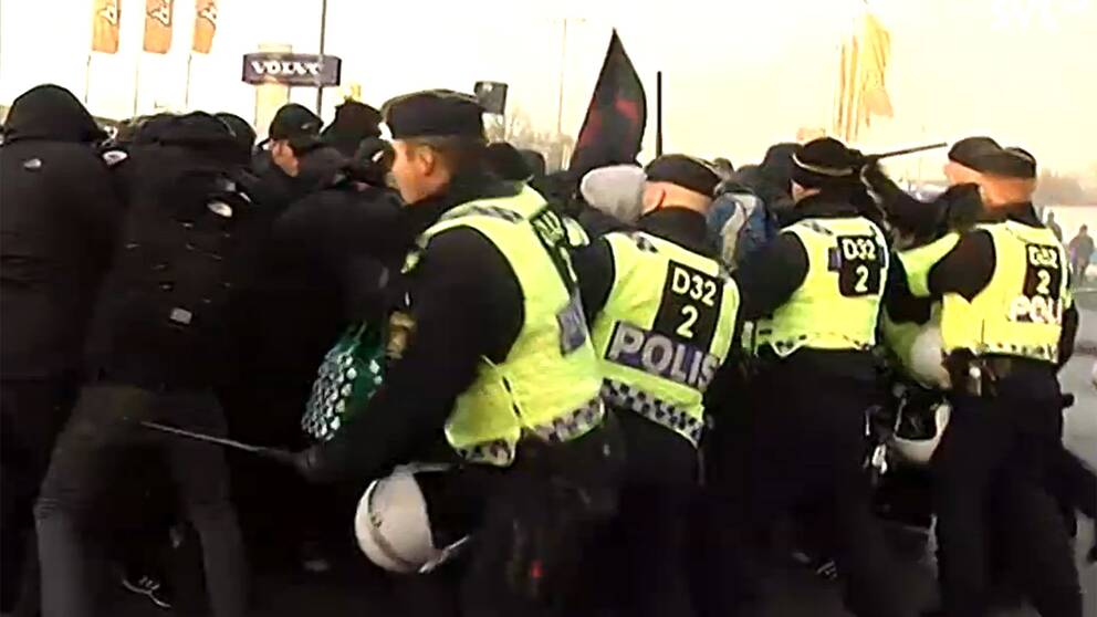 Polis föser tillbaka maskerade demonstranter nära lokalerna där Sverigedemokraterna håller sina landsdagar.