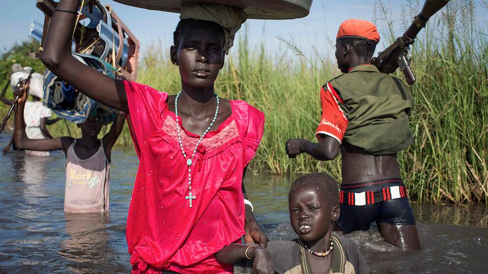 Människor tar sig genom översvämmade träskmarker i Sydsudan på jakt efter mediciner och mat.
