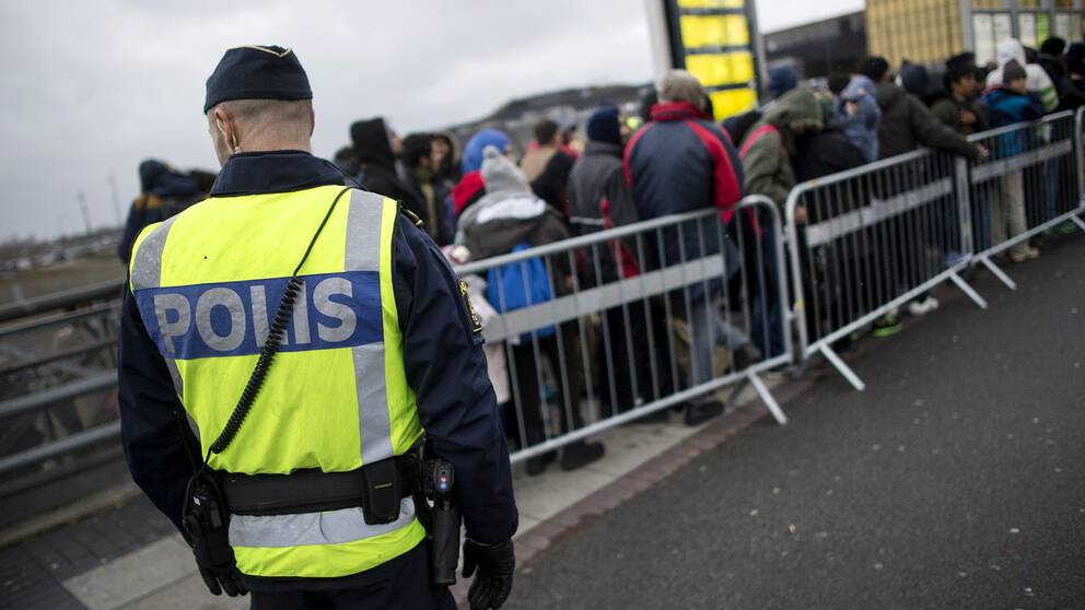 Polis bevakar flyktingar som anlänt till Sverige via tåg.