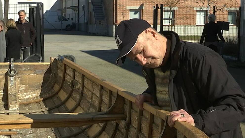 Gösta Ekwall tittar på en träbåt