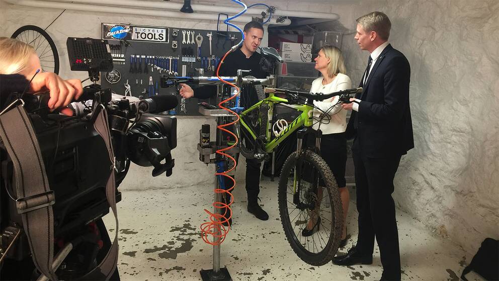 Ministrarna Per Bolund (MP) och Magdalena Andersson (S) i en cykelverkstad. Regeringen vill göra det billigare att få reparationer utförda.