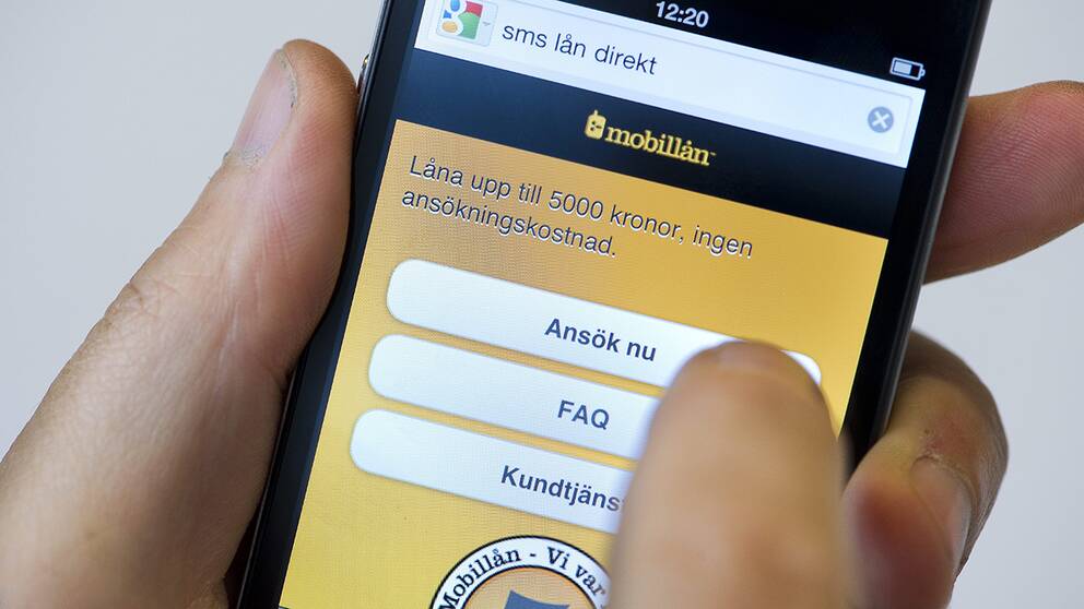 En person håller på att ta ett sms-lån med hjälp av sin mobiltelefon.