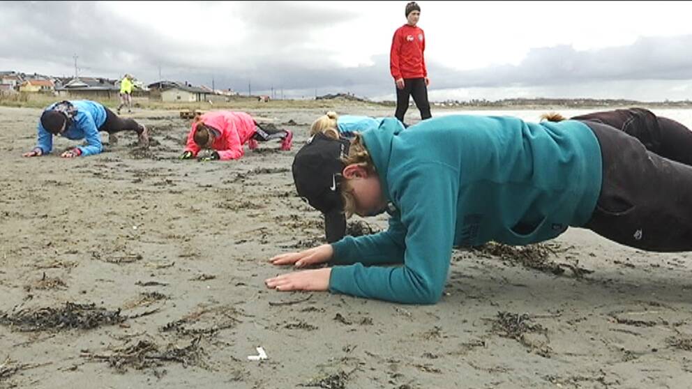 Barn tränar armhävning på stranden i Varberg.