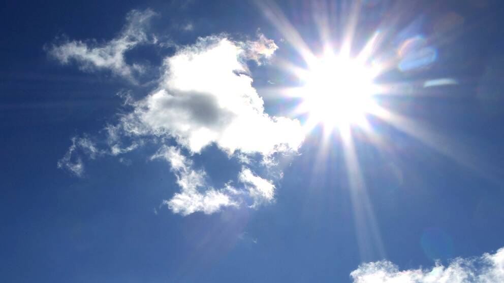 Sol och moln på en blå himmel