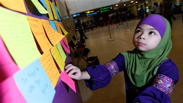 Sex år gamla Aris Marissa sätter upp en post it-lapp med en text till passagerarna på AirAsia-flyget.