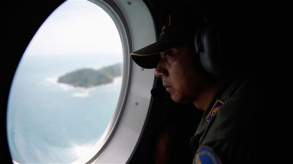 En besättningsman på kustbevakningen tittar ut genom fönstret under det pågående sökarbetet.