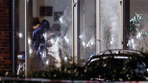 Polisens tekniker undersöker den sönderskjutna entrén till kulturhuset. Foto: TT