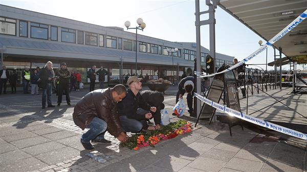 9 Flera personer lägger blommor vid polisens avspärrningar på Värväderstorget på Hisingen i Göteborg. Foto: TT