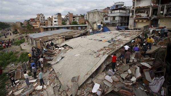 Människor samlas kring ett kollapsat hus i Katmandu. Foto: TT
