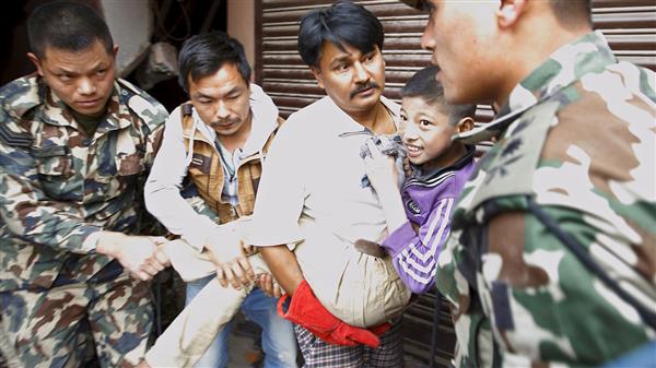 En pojke ler efter att ha räddats ur rasmassorna från ett kollapsat hus i Katmandu. Foto: TT