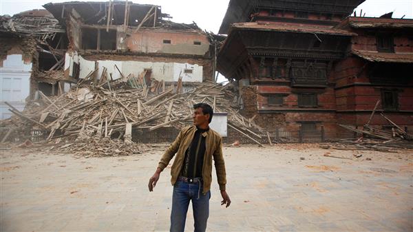 En man står utanför en av de rasade byggnaderna i Katmandu. Foto:TT