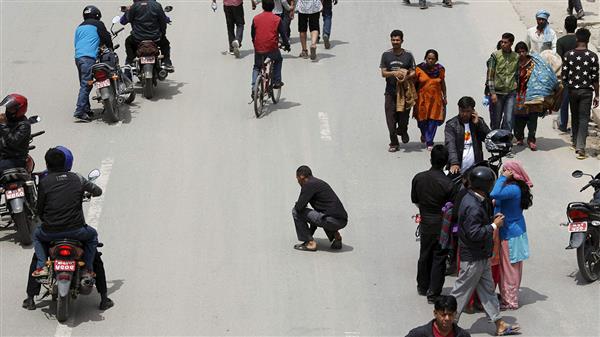 Många blev skrämda när marken än en gång började skaka. Här sätter sig en man ner på gatan under efterskalvet som inträffade tidigare dag. Foto: TT