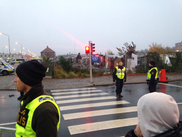 Boende som är kvar inne i lägret klättrar på stängslen och ropar till demonstranterna på utsidan. Malmö Stads personal har ännu inte anlänt till platsen.