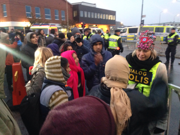 Dialogpoliser försöker förklara och lugna ned situationen när demonstranter skakar stängslen.