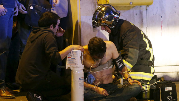 Sjukvårdspersonal tar hand om en skadad man utanför konsertlokalen Bataclan där gisslandramat nu uppges vara över. Foto: TT