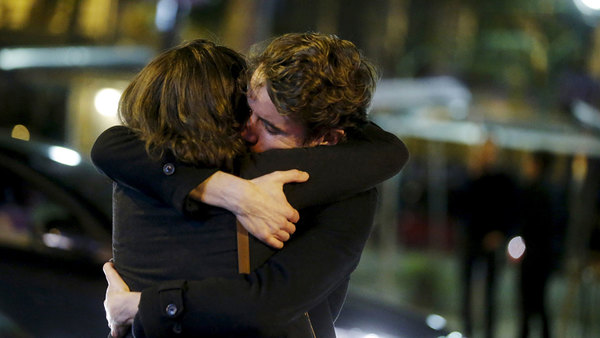 Två personer omfamnar varandra utanför konsertlokalen Bataclan i Paris, där många personer dödats i kväll. Foto: TT