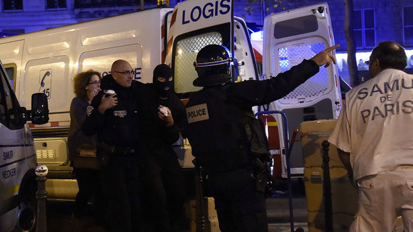 En skadad polis tas omhand utanför konsertlokalen Bataclan, efter att man stormat byggnaden. Foto: TT