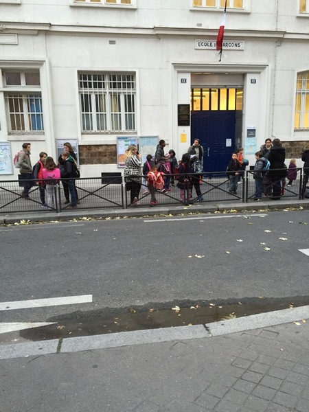 Barn och föräldrar väntar på att komma in i en skola i Paris.