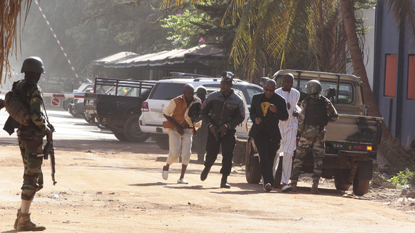 Säkerhetsstyrkor eskorterar en man från ingången till Radisson Blu i Bamako.