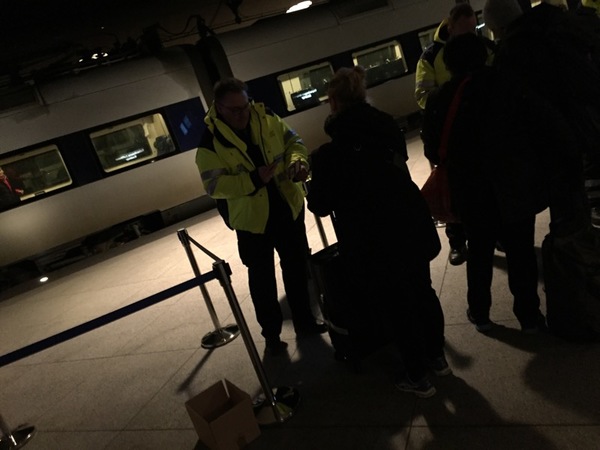 Kontrollanterna fotograferar resenärernas ID-kort. Nu går det undan eftersom det står ett tåg på perrongen och är klart för avfärd.