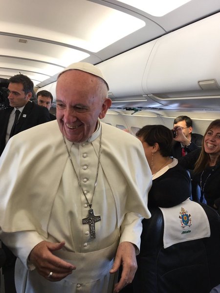Påven hälsar på journalisterna på planet. 

