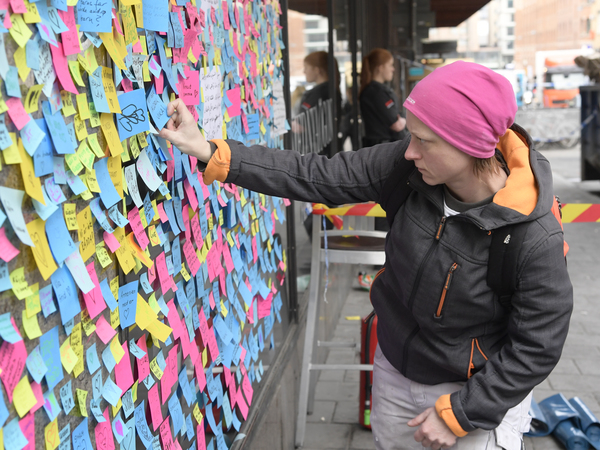Maria Schwebke vid en minnestavla med meddealndet på post-itlappar till offren för lastbilsattacken på Drottninggatan. Foto: TT