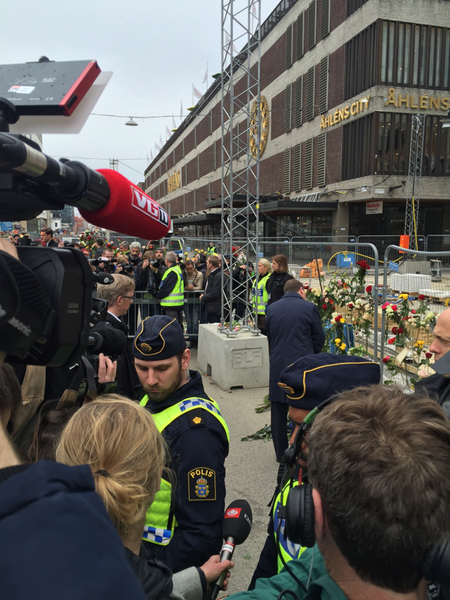 Statsministern klappar en av poliserna på axeln innan han går vidare och lämnar sina blommor.