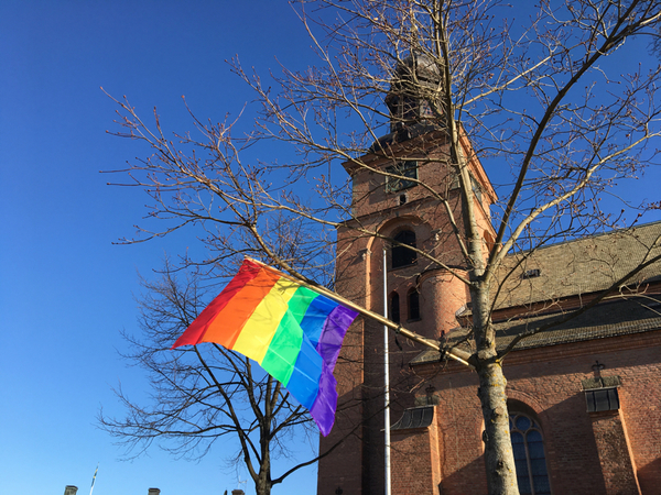 Pride-flaggan vajar från träd utanför Kristine kyrka.