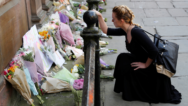 En kvinna lägger ner blommor i centrala Manchester för att hedra offren. Foto: TT