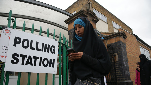 Vallokalerna öppnade klockan 08 på torsdagen. Här går en kvinna förbi en vallokal i Ilford i östra London. Foto: TT